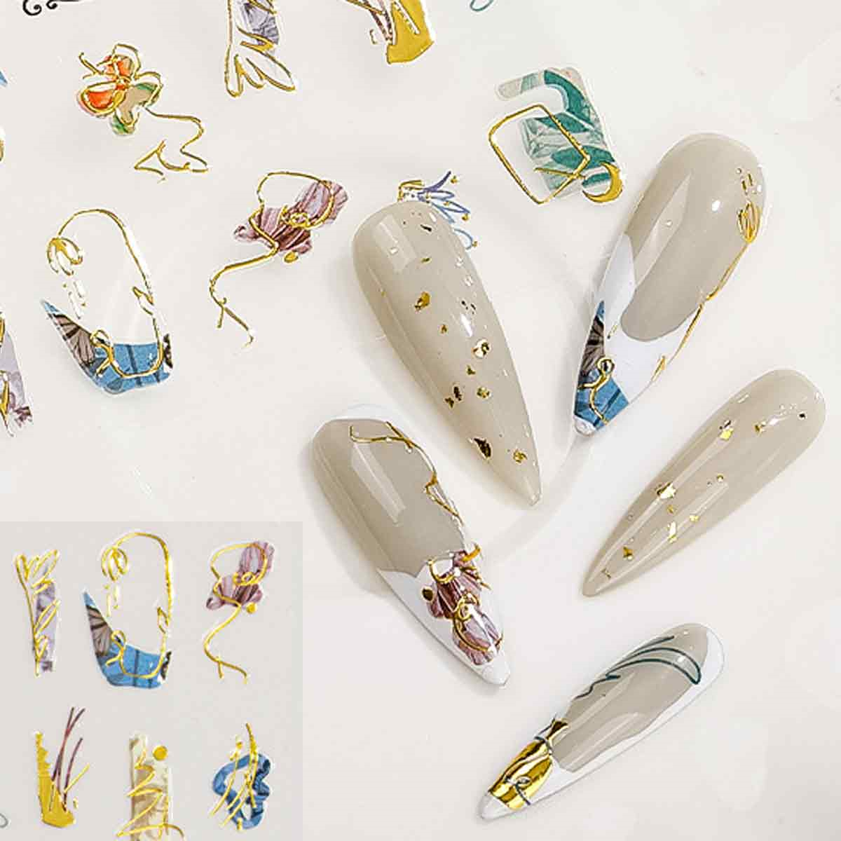 Nagelkunst mit beigen Nägeln, Goldflocken und floralen Mustern. Mehrere Nägel sind sichtbar, einige mit dekorativen Aufklebern.