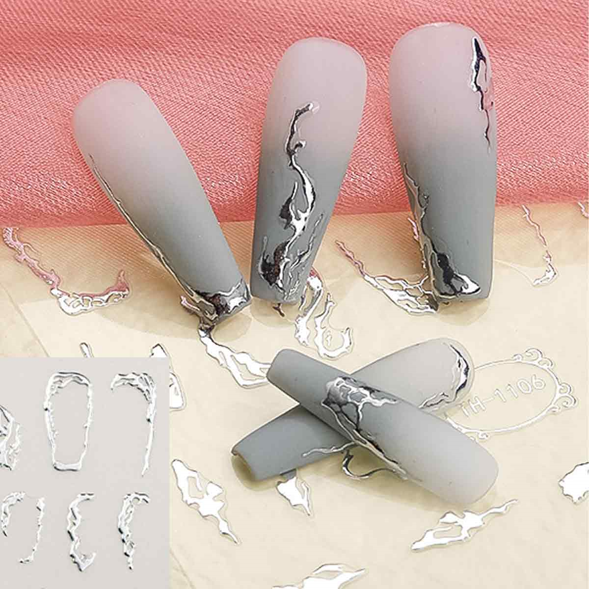Künstliche Nägel mit silbernem Wirbeldesign und etwas losem Nageldesign.