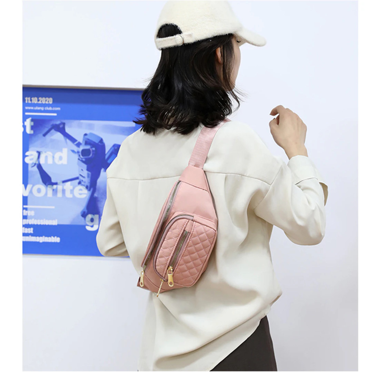 Frau von hinten mit rosa Bauchtasche, weißer Mütze und Hemd, mit Poster im Hintergrund.