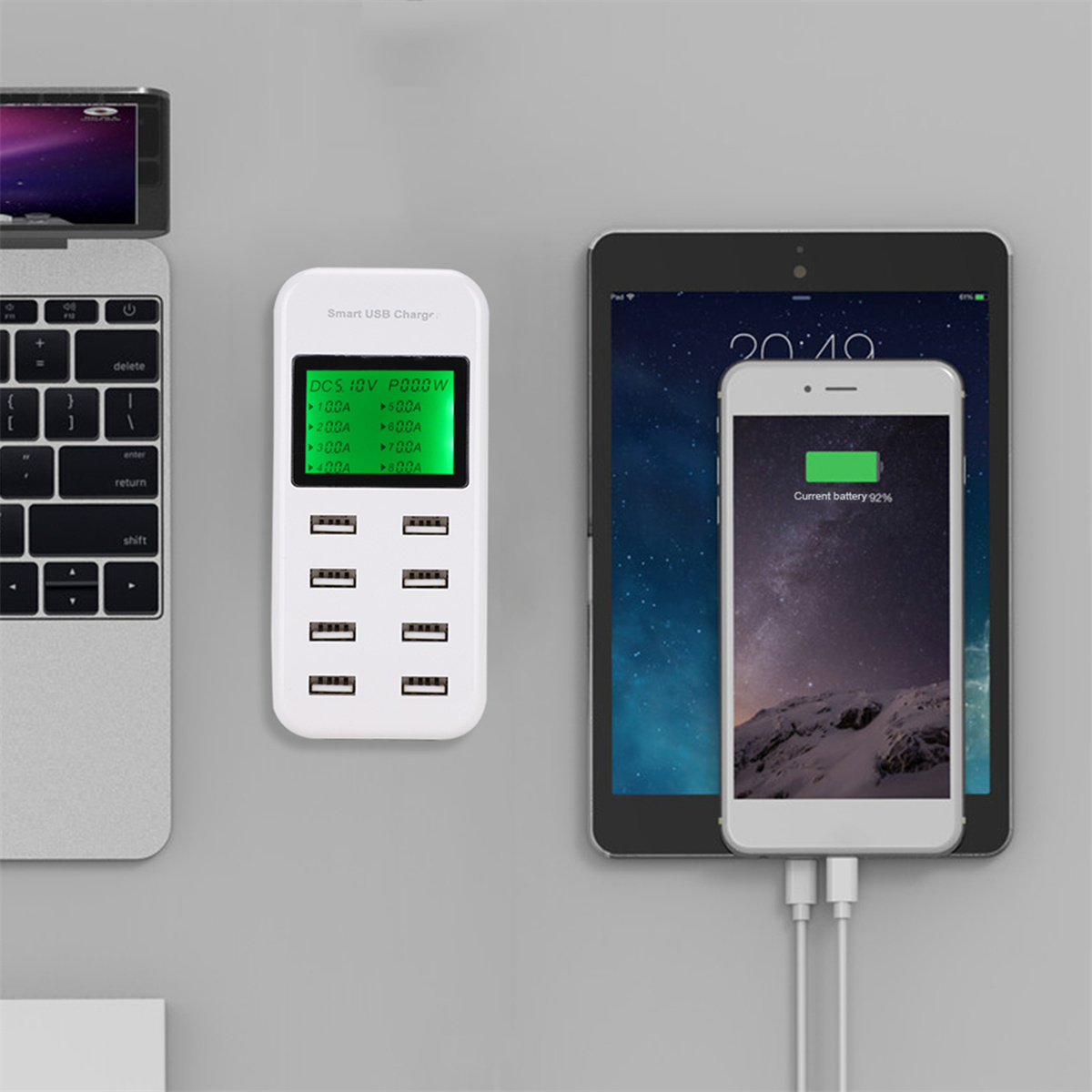 Eine weiße Ladestation mit mehreren USB-Anschlüssen, die ein Tablet und ein Telefon auflädt. Ein Laptop ist ebenfalls sichtbar.