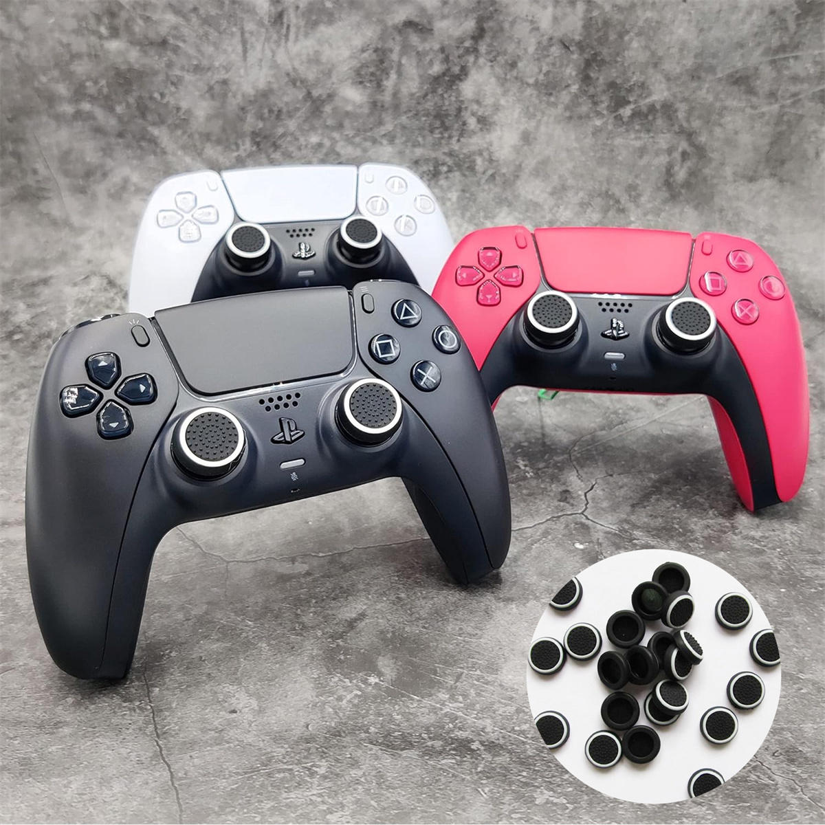 Drei Gamecontroller auf einer Oberfläche. Einer schwarz, einer weiß und einer rot. Kleine schwarze Knopfabdeckungen.