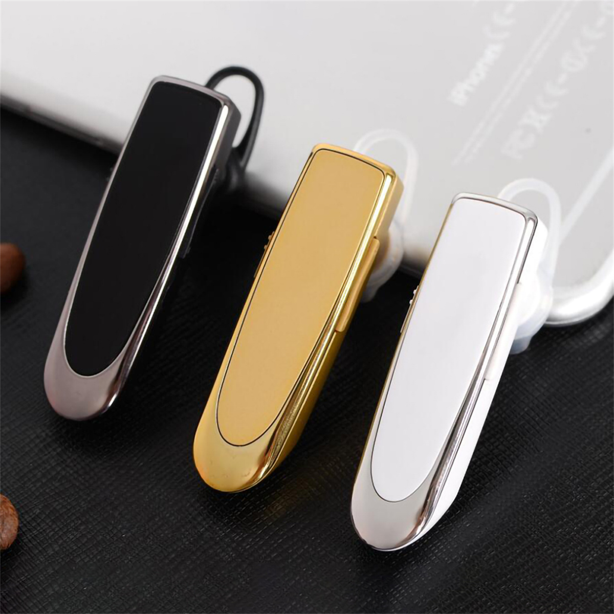 Drei kabellose Bluetooth-Headsets in Schwarz, Gold und Weiß, schräg auf einer Oberfläche.