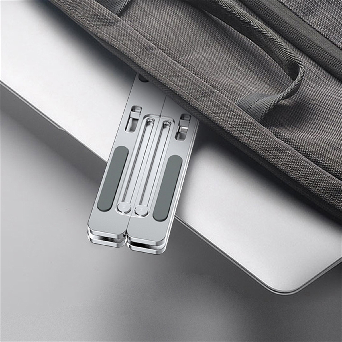 Silberner Laptopständer teilweise in einer grauen Laptoptasche auf einem silbernen Laptop.