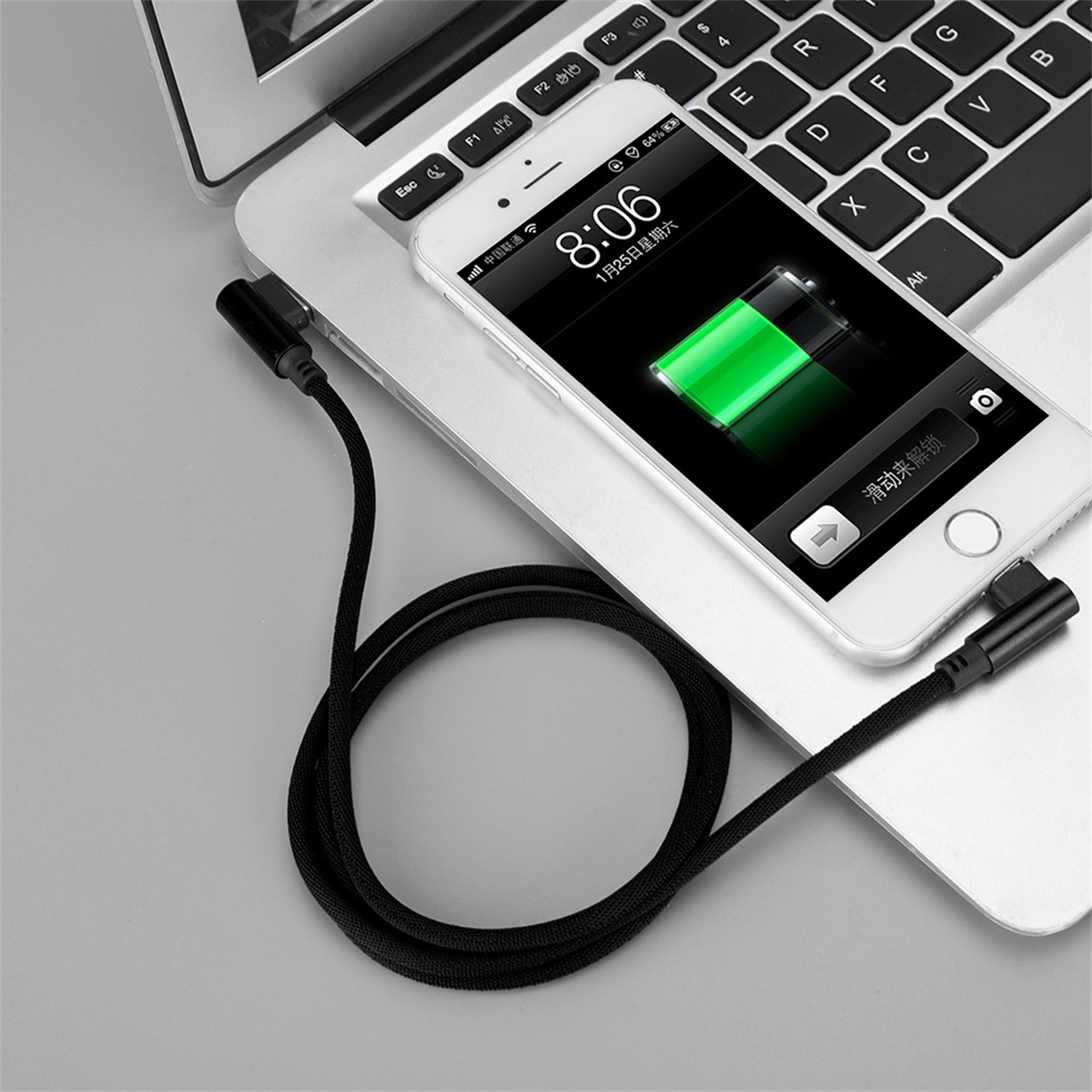 Ein schwarzes USB-C-Kabel, das mit einem Laptop und einem Smartphone verbunden ist, mit Ladebildschirm.