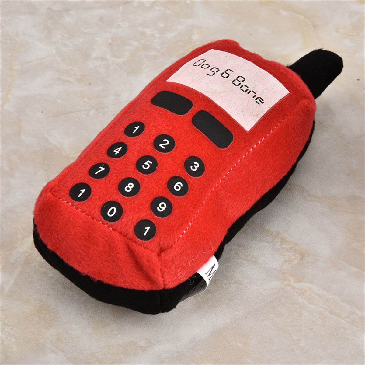 Rotes Plüsch-Hundespielzeug in Form eines Retro-Telefons. Das Spielzeug hat Zahlen und den Text 'Dog & Bone'.