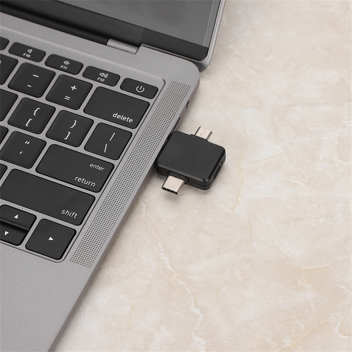 Schwarzer Adapter, der in einen silbernen Laptop eingesteckt ist. Der Adapter ist USB-C zu mehreren Anschlüssen.