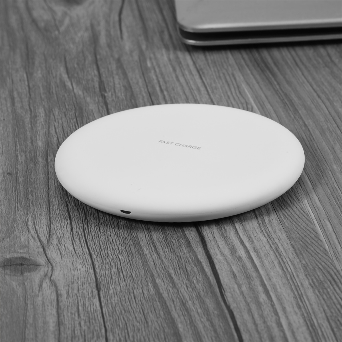 Weißes kabelloses Ladegerät auf Holzoberfläche. Das Ladegerät hat "FAST CHARGE".