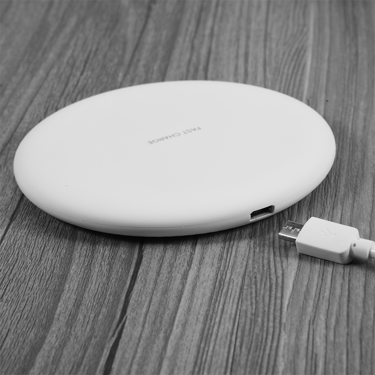 Weißes kabelloses Ladegerät mit USB-Kabel. Auf Holzoberfläche.