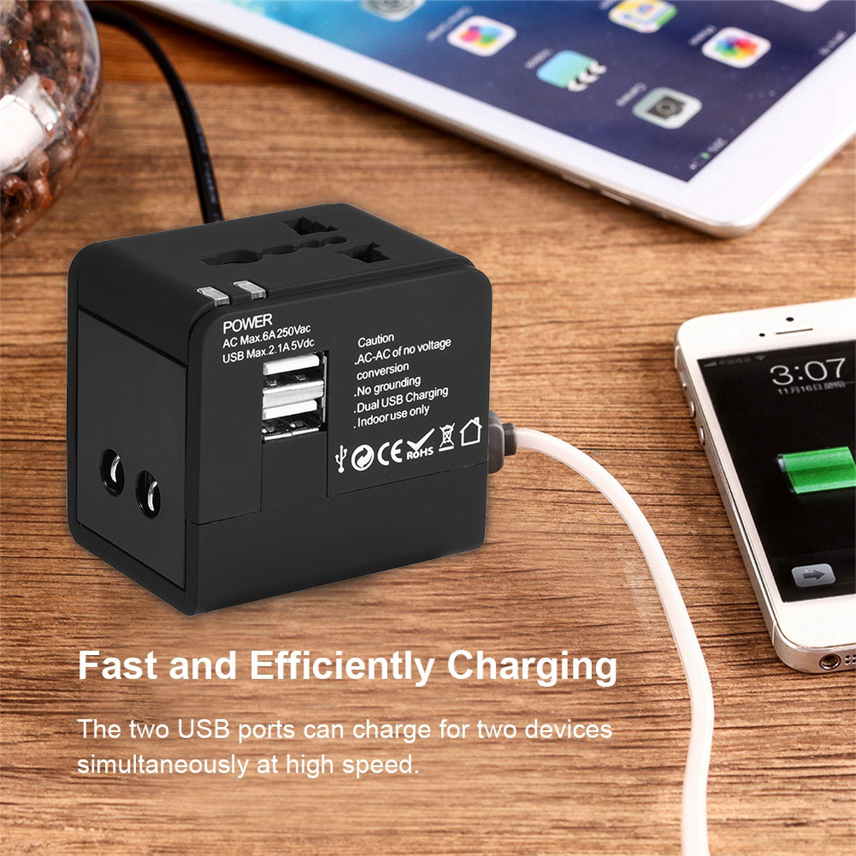 Ein schwarzer Reiseadapter mit USB-Anschlüssen lädt ein Tablet und ein Telefon auf.