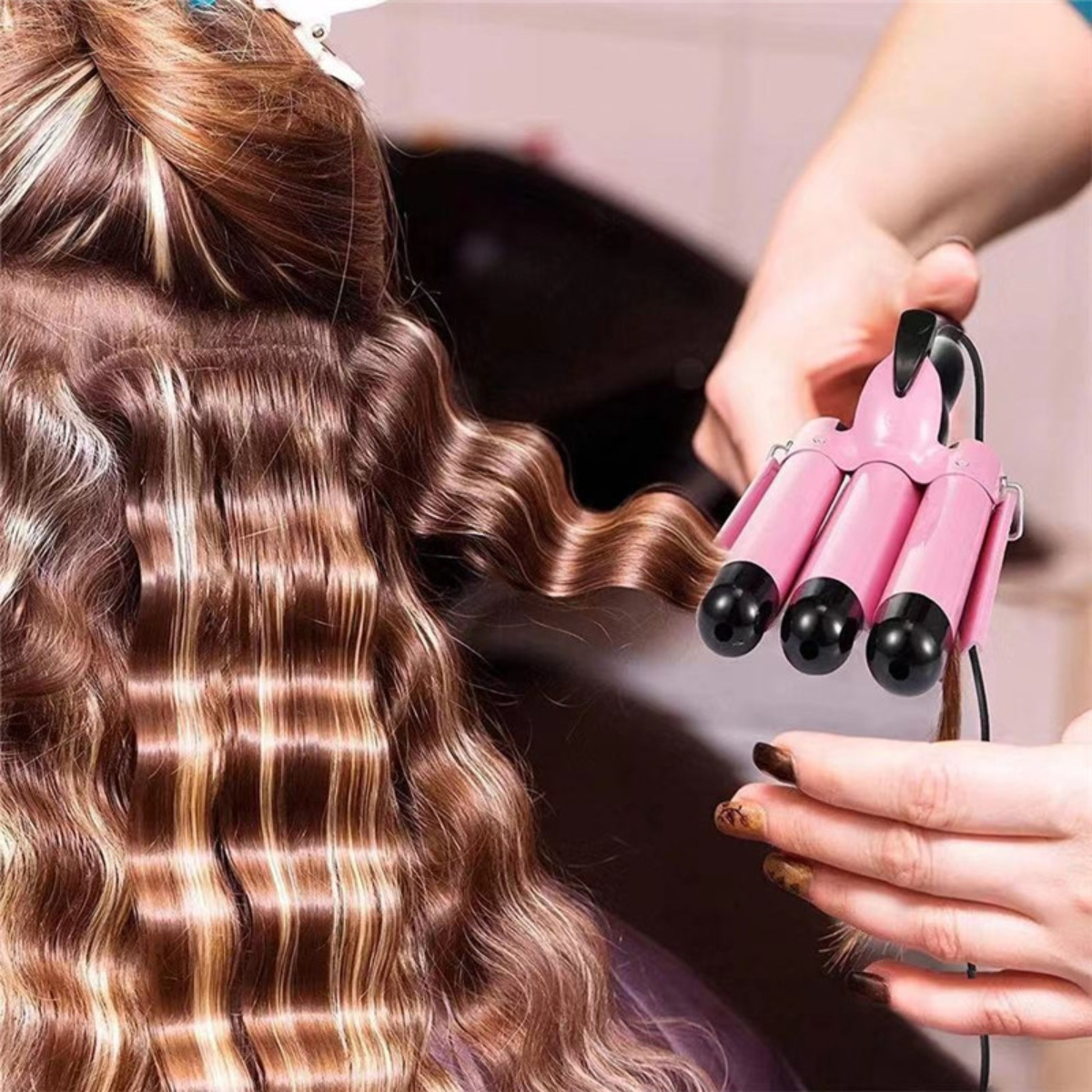 Eine Person verwendet einen rosa Lockenstab auf braunem Haar. Das Haar wird gewellt.
