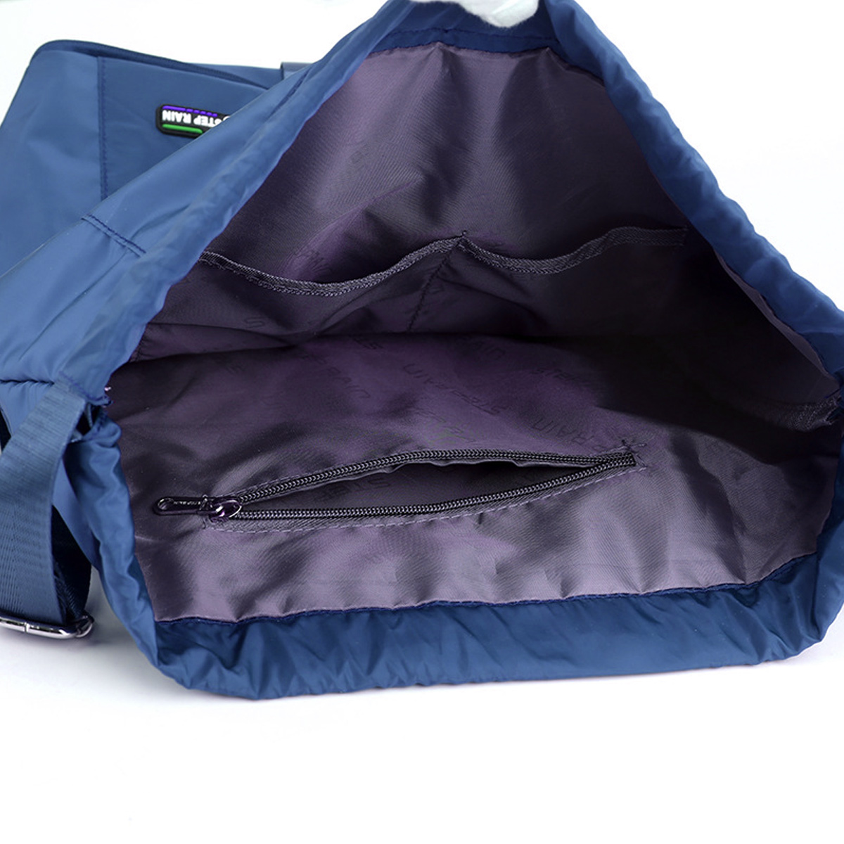 Blaue Nylon-Umhängetasche, offen, mit Innentaschen und einer Reißverschlusstasche, auf weißem Hintergrund.