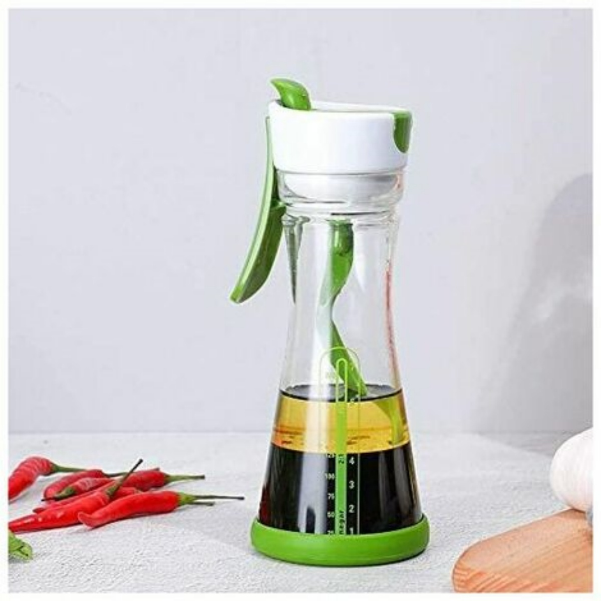Eine Glasflasche mit grünen Akzenten enthält Öl und Essig. Rote Paprika liegen daneben.
