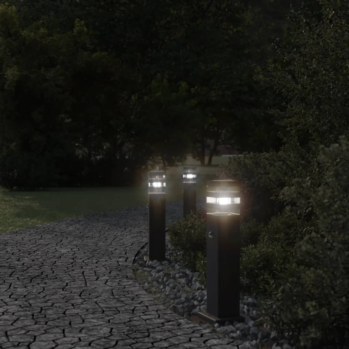 Weg mit beleuchteten Pollerleuchten bei Dämmerung, Bäume und Büsche im Hintergrund.