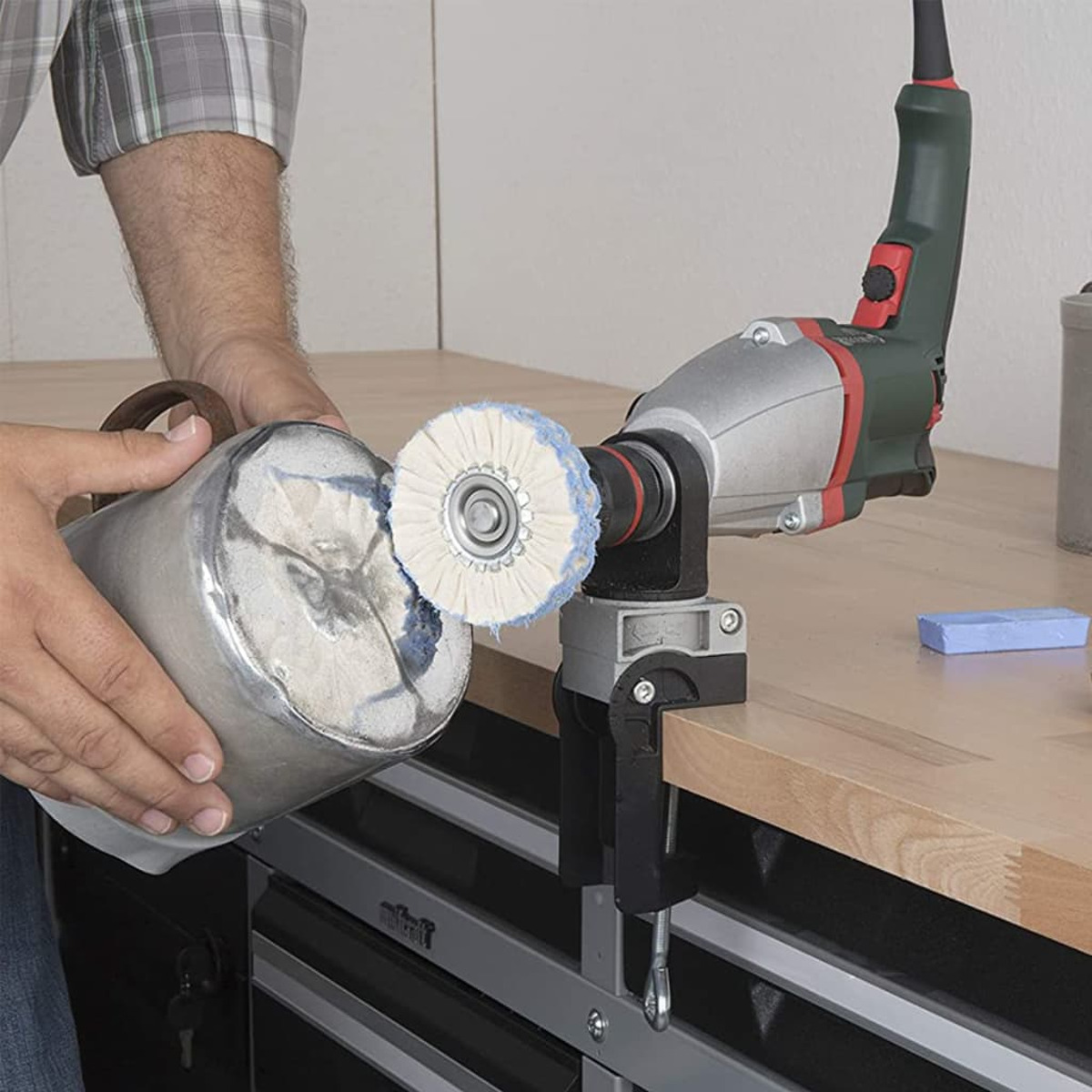 Person verwendet eine Poliermaschine auf einem Metallobjekt. Maschine ist an der Werkbank befestigt.