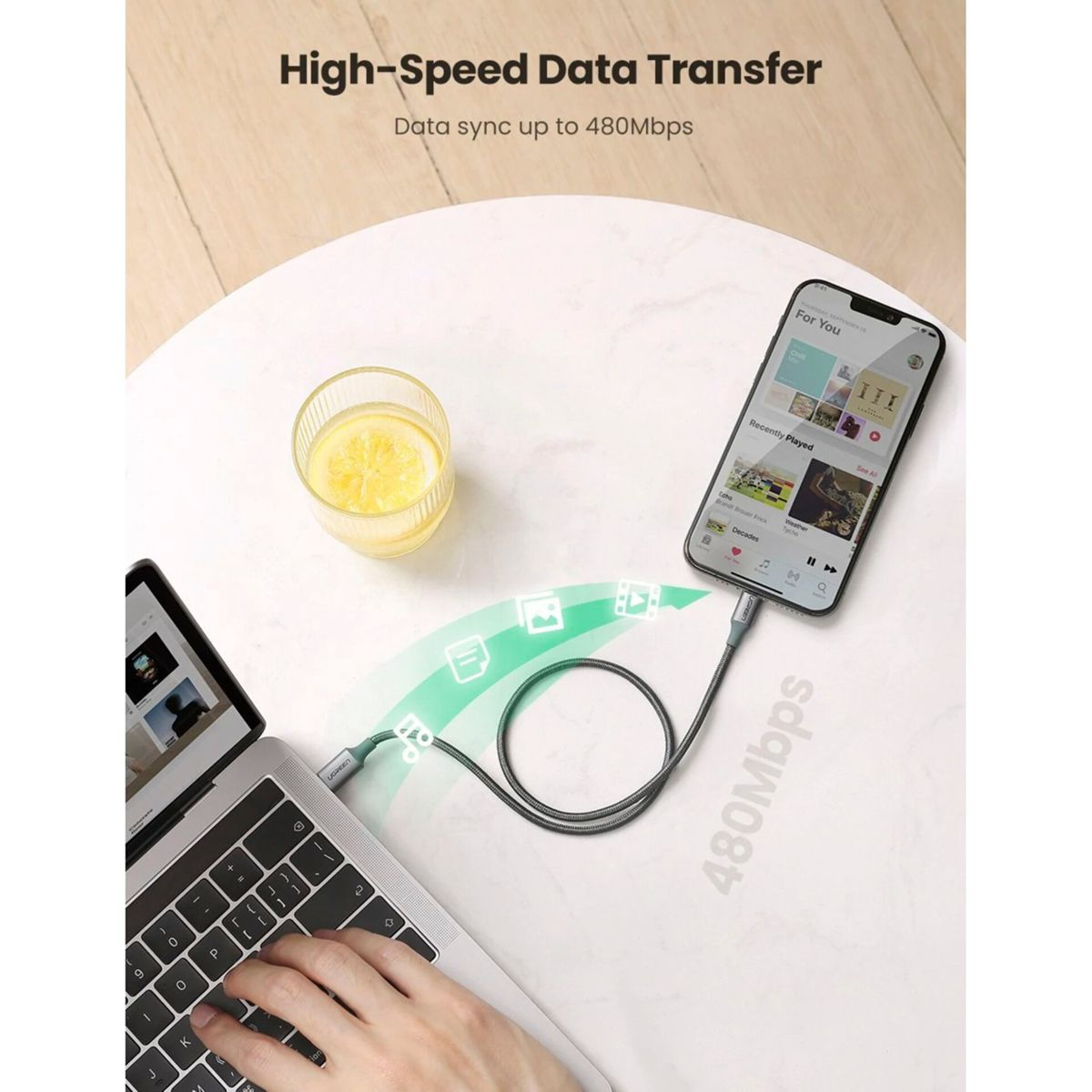 Smartfon podłączony do laptopa za pomocą kabla do przesyłania danych, z ikonami przesyłanych plików.