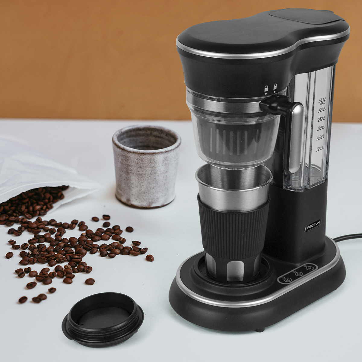 Czarny ekspres do kawy z filiżanką i ziarnami kawy. Obok ceramiczny kubek i ziarna.