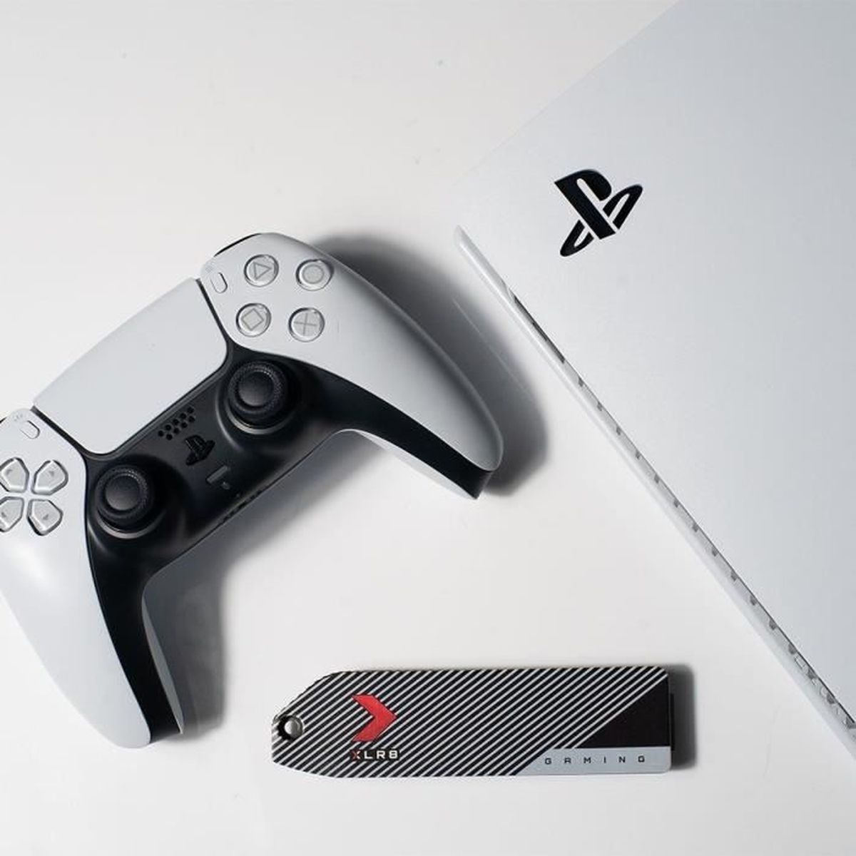 Biała konsola PlayStation 5, kontroler i czarno-biały dysk SSD do gier.