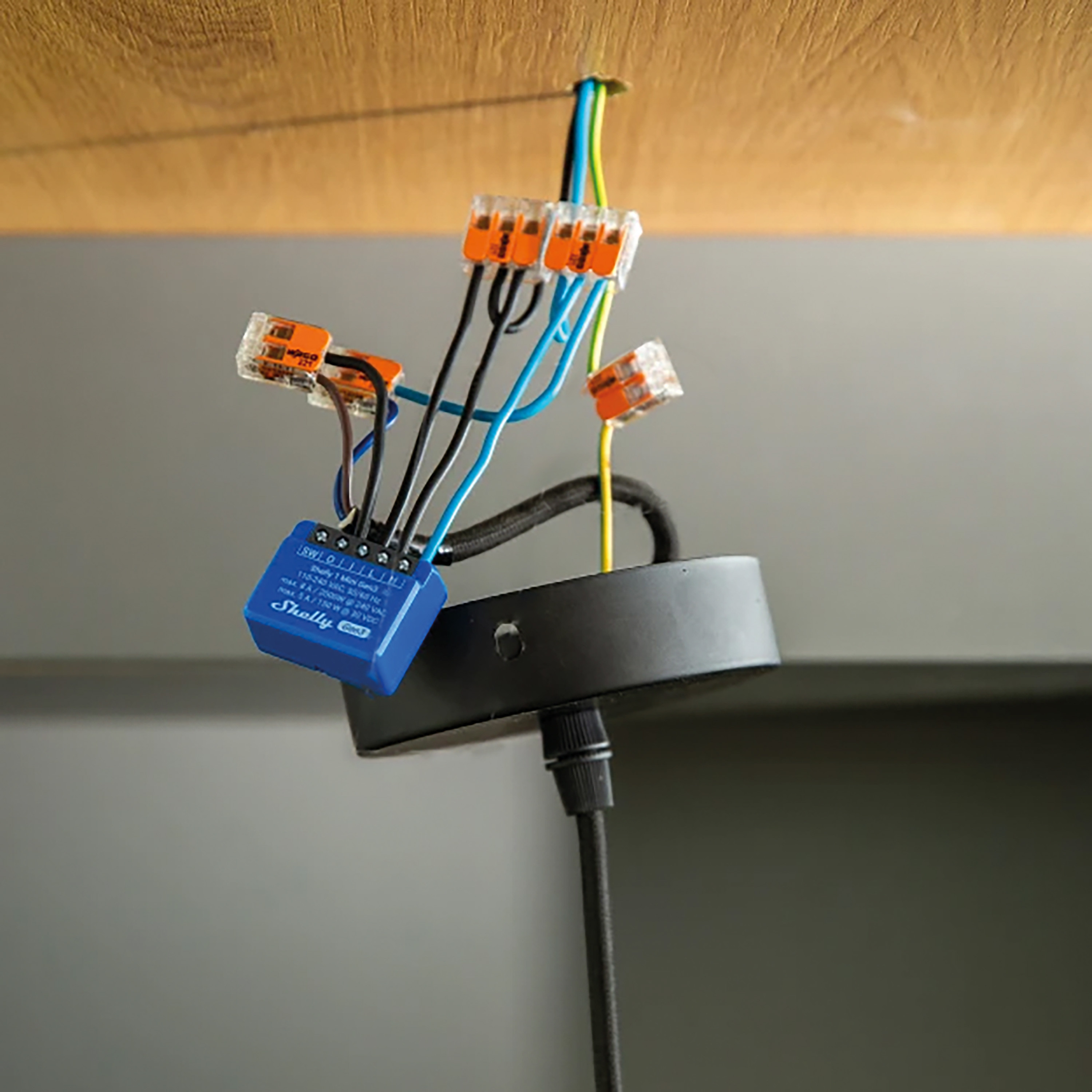 Instalacja okablowania elektrycznego z przewodami, złączami i niebieskim urządzeniem Shelly.