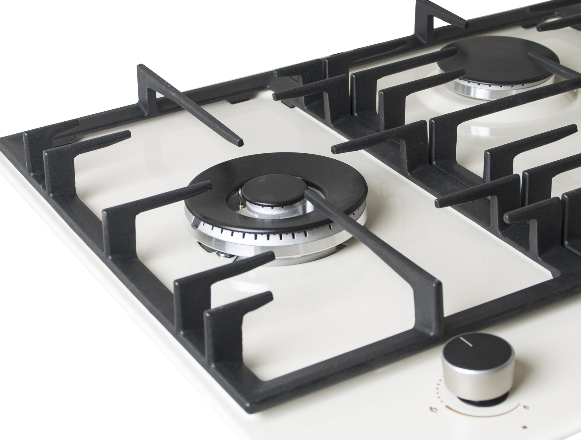 Close-up of a white cooktop with black grates and burners.