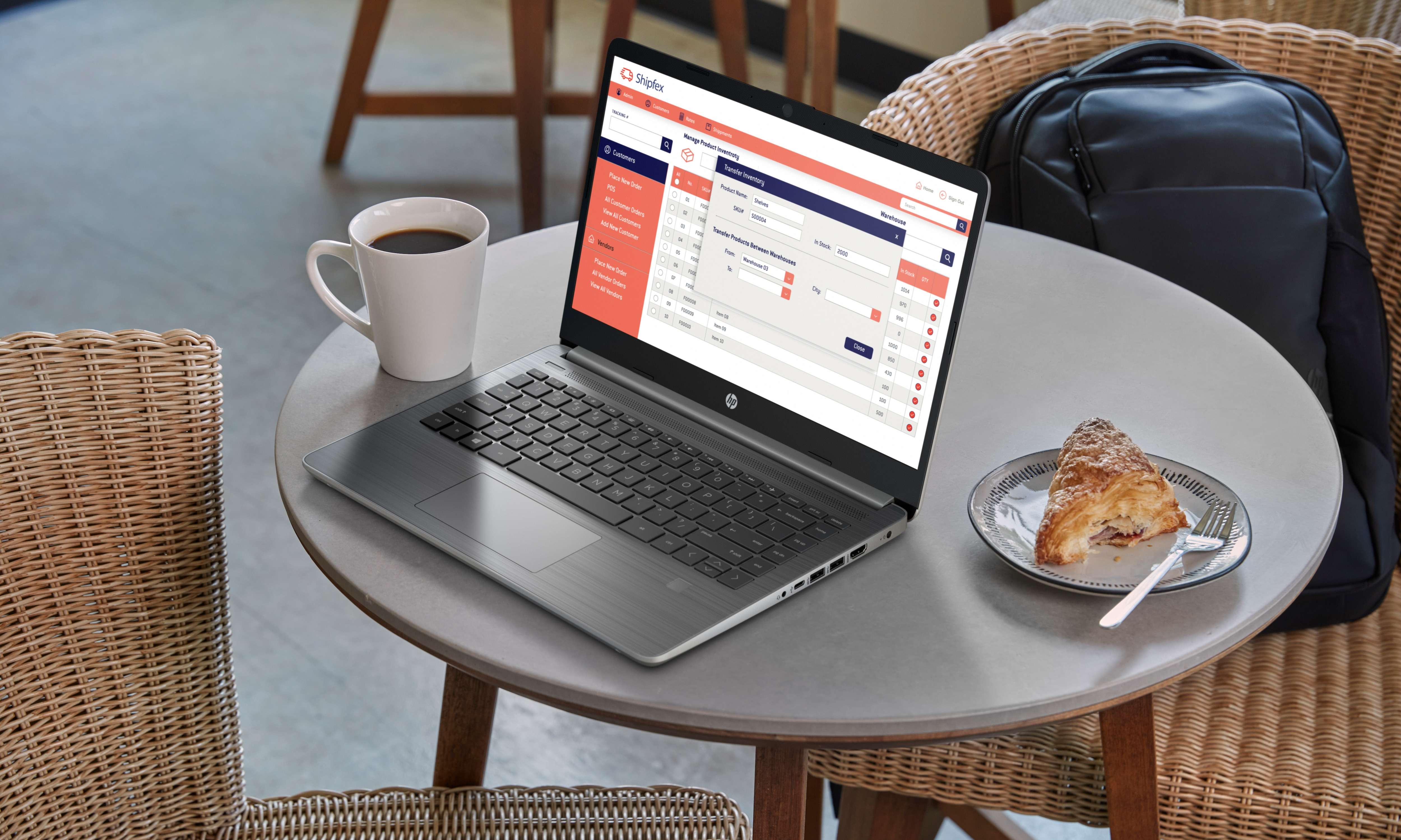 Un laptop su un tavolo con una tazza di caffè e un pasticcino. Lo schermo mostra un'interfaccia.