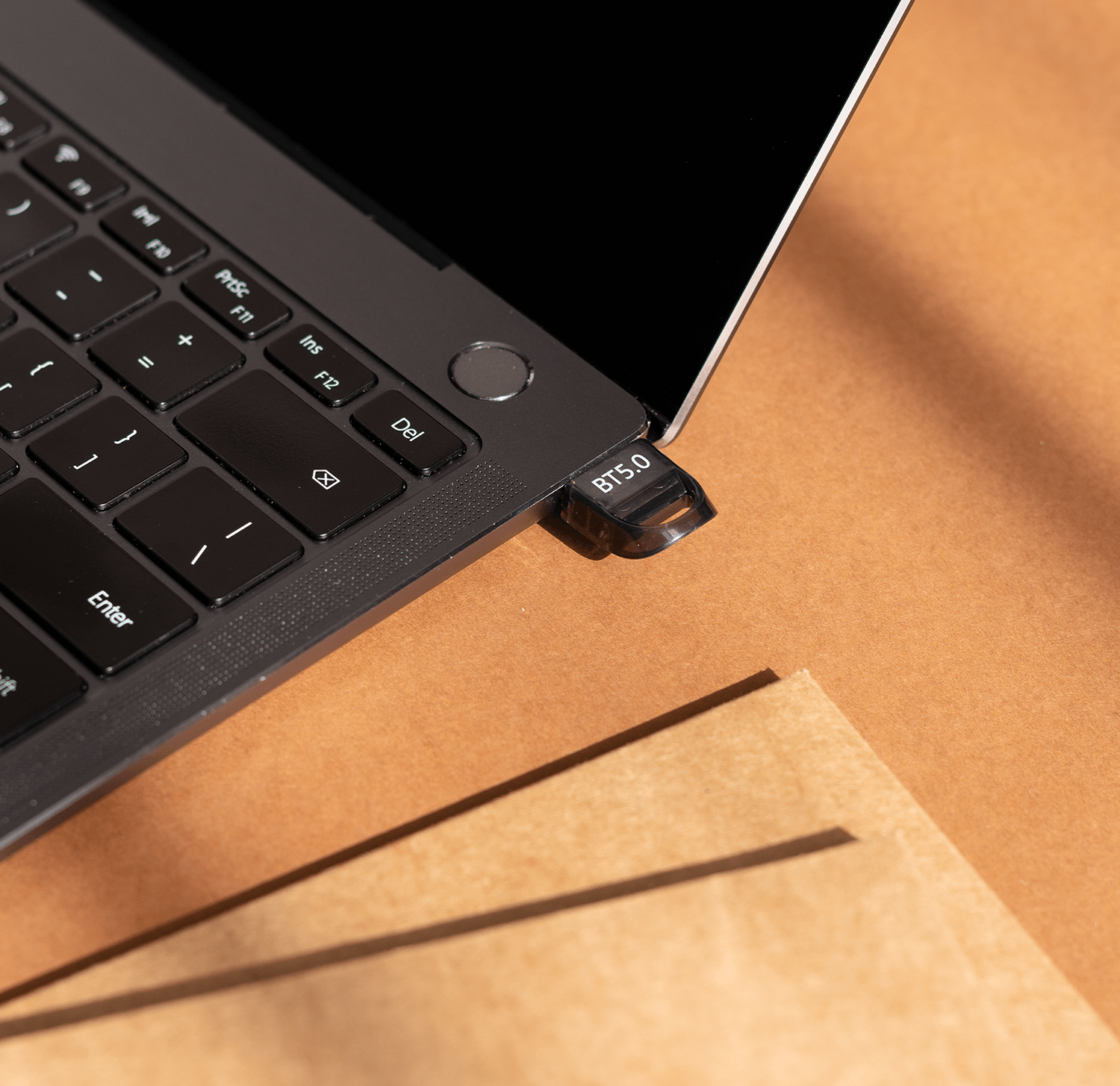 Zbliżenie laptopa z podłączonym dyskiem USB. Na dysku napis BT 5.0.