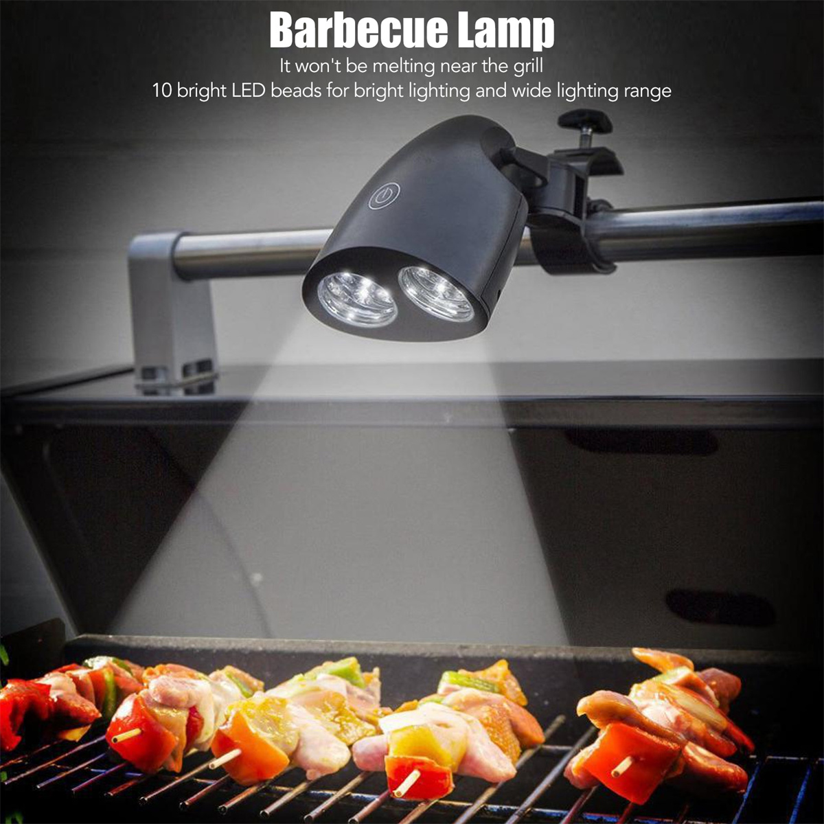 Schwarze Grilllampe, befestigt an einem Grill, beleuchtet Spieße mit Essen, das auf dem Grill zubereitet wird.