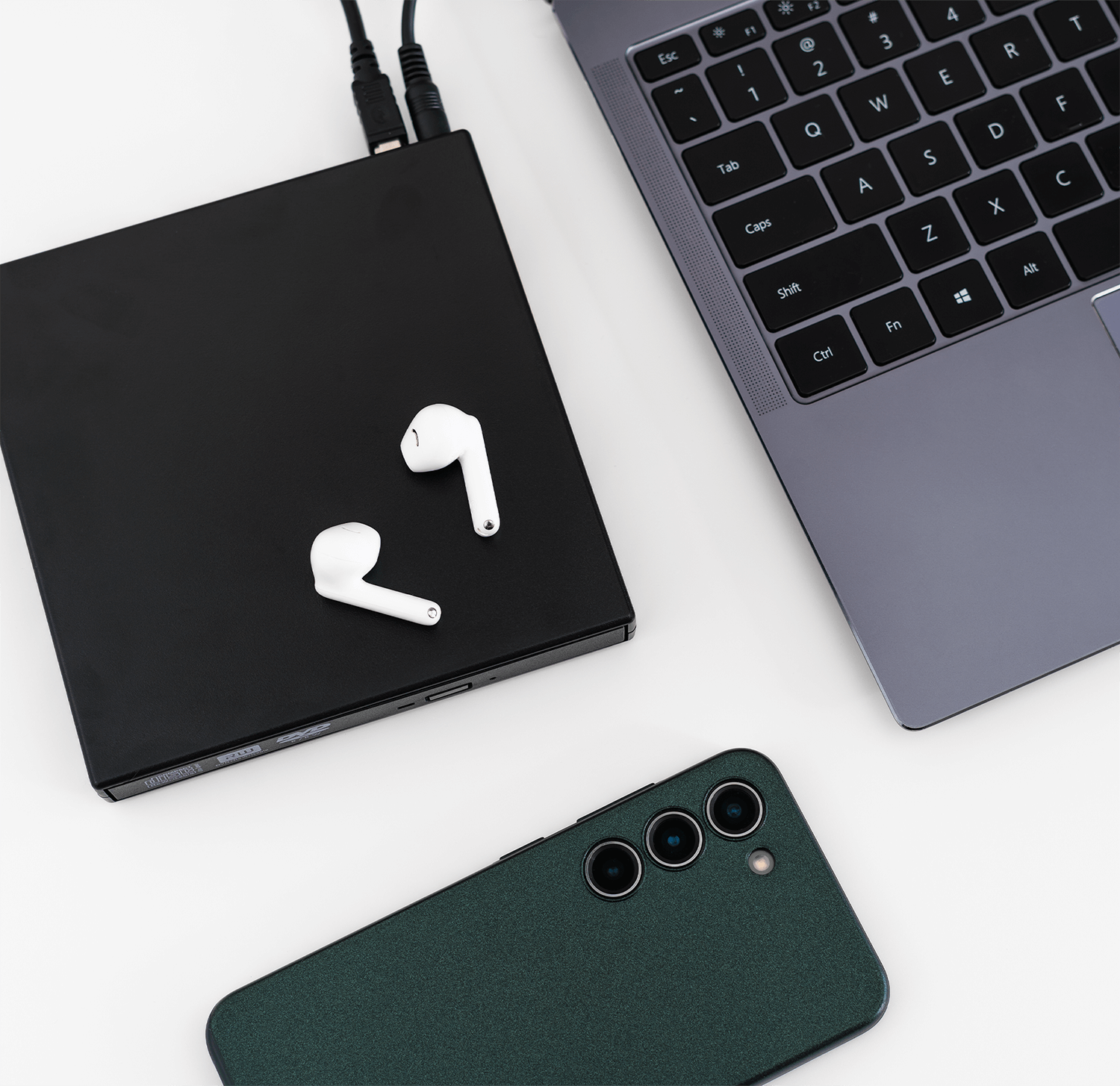 Laptop, słuchawki, telefon i czarny napęd. Białe tło.