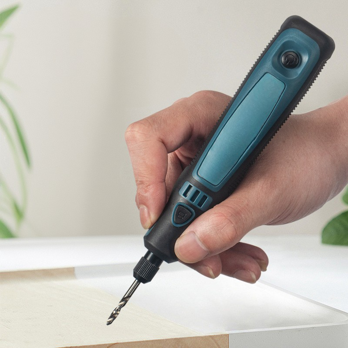 Eine Hand hält einen blau-schwarzen Bohrer und bohrt in ein Holzstück. Der Bohrer ist türkis.