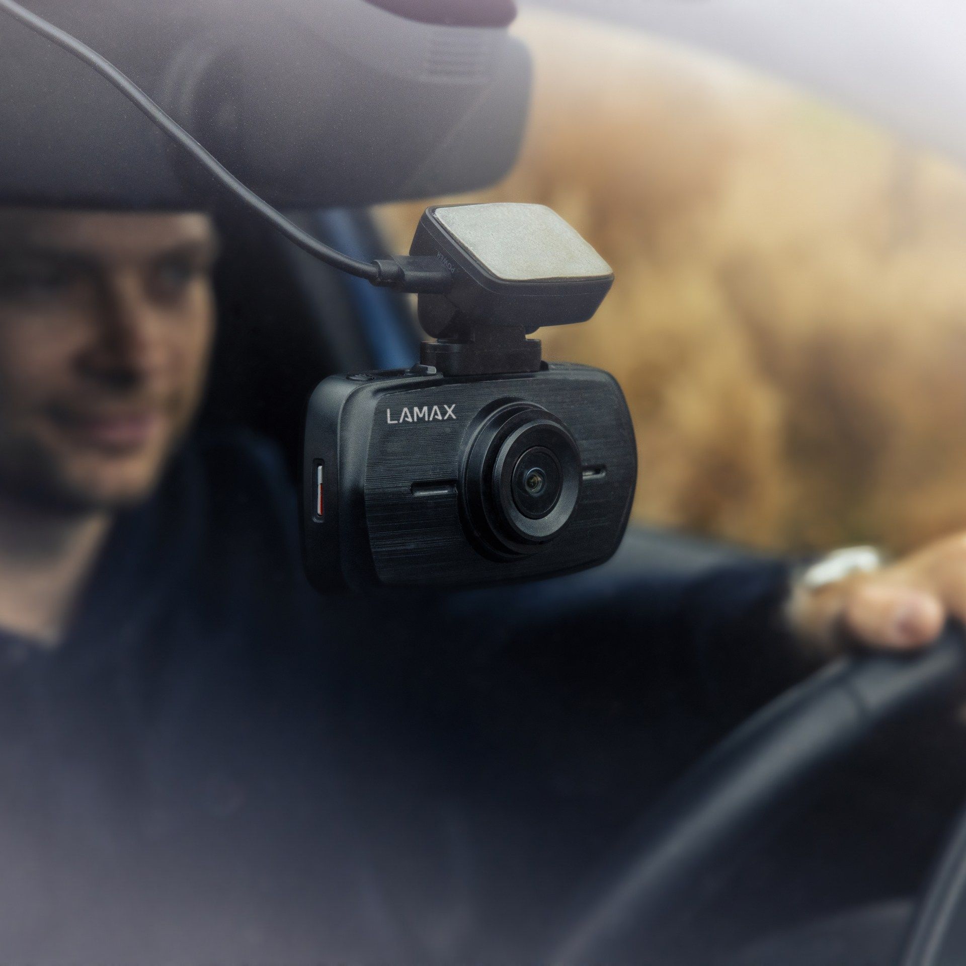 Eine im Auto montierte Dashcam an der Windschutzscheibe. Im unscharfen Hintergrund ist ein Mann zu sehen.