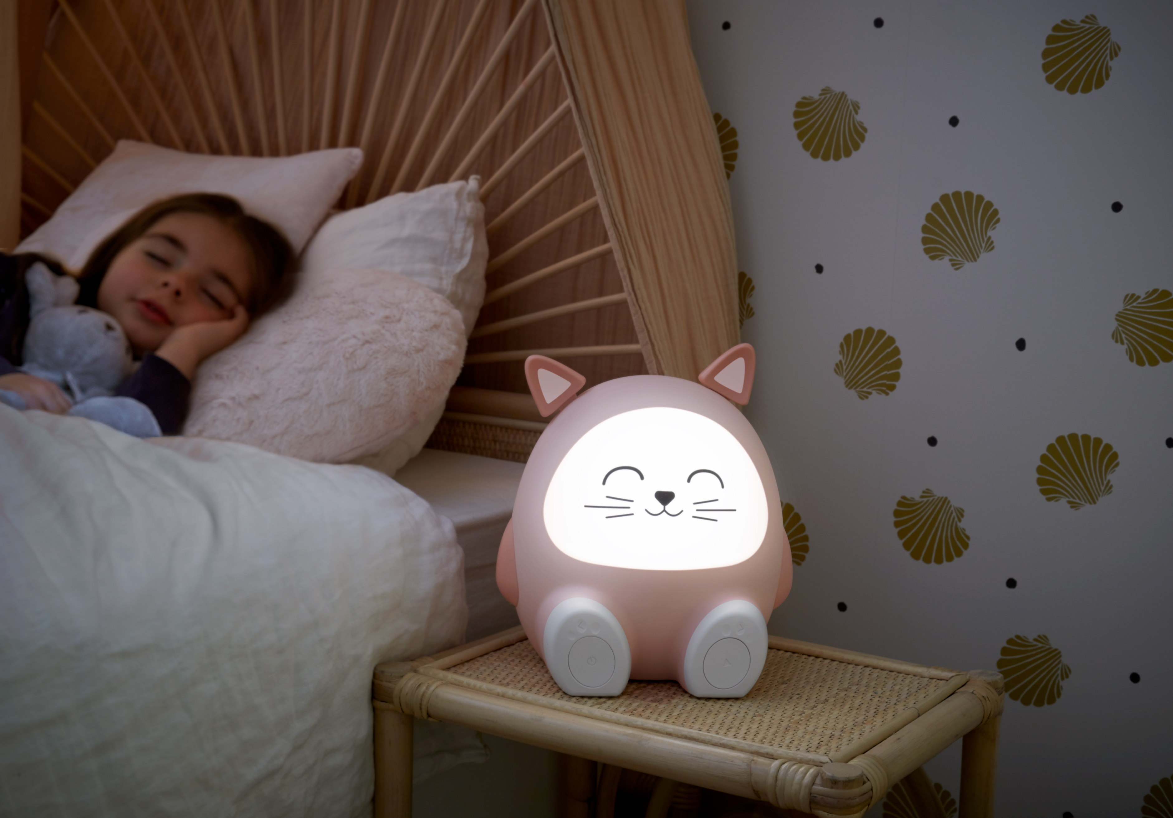 Ein Kind schläft im Bett, beleuchtet von einem rosa katzenförmigen Nachtlicht.