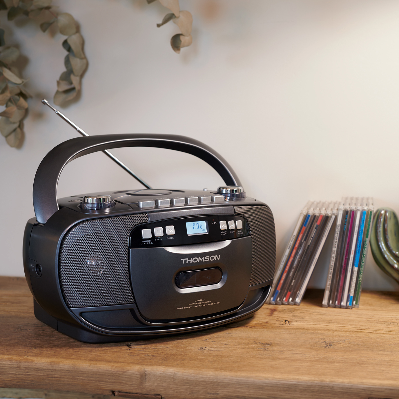 Czarny radioodtwarzacz z uchwytem, odtwarzacz CD i płyty CD na drewnianej powierzchni, białe tło.