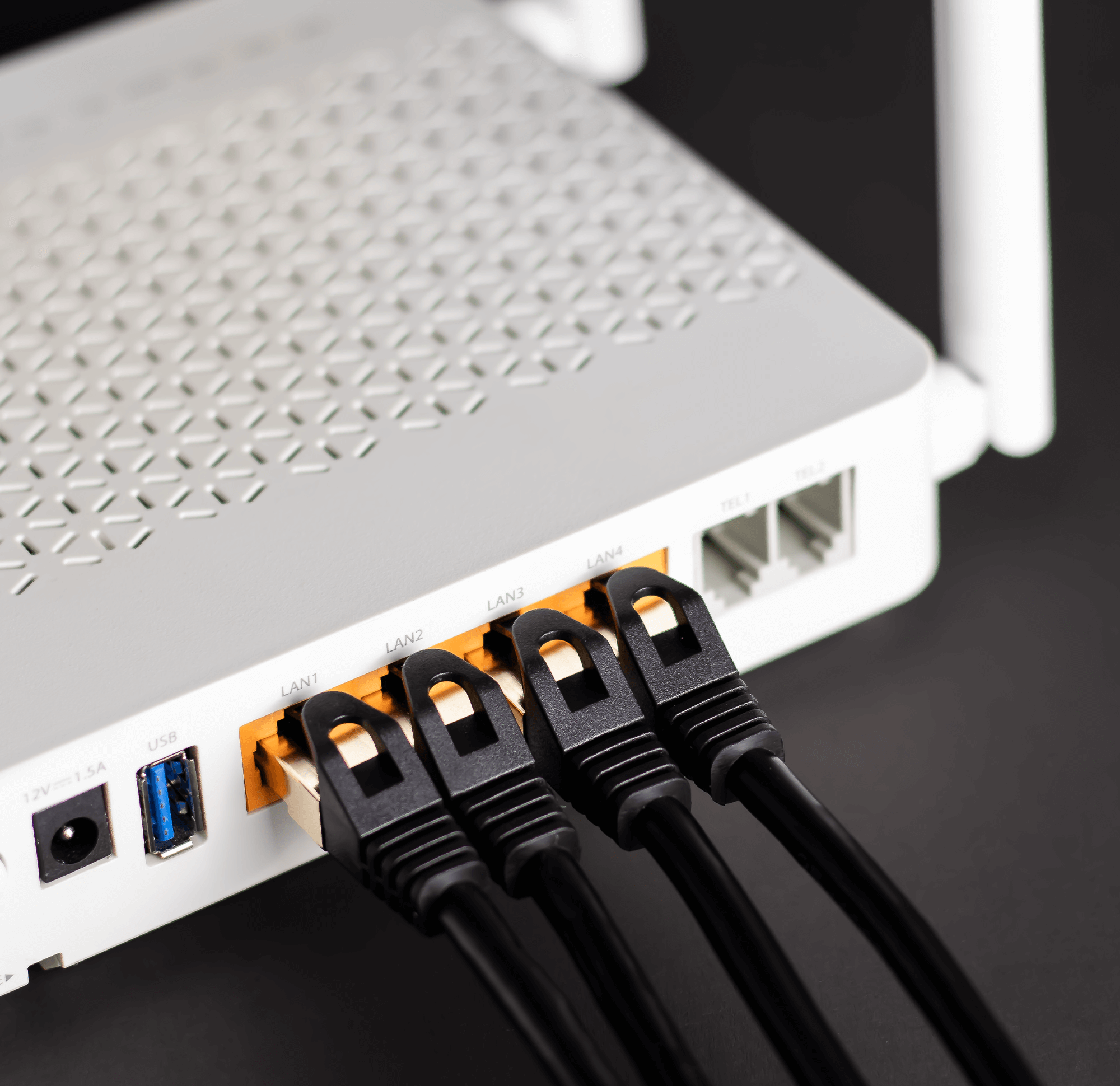 Biały router z czterema czarnymi kablami podłączonymi. Router ma anteny.