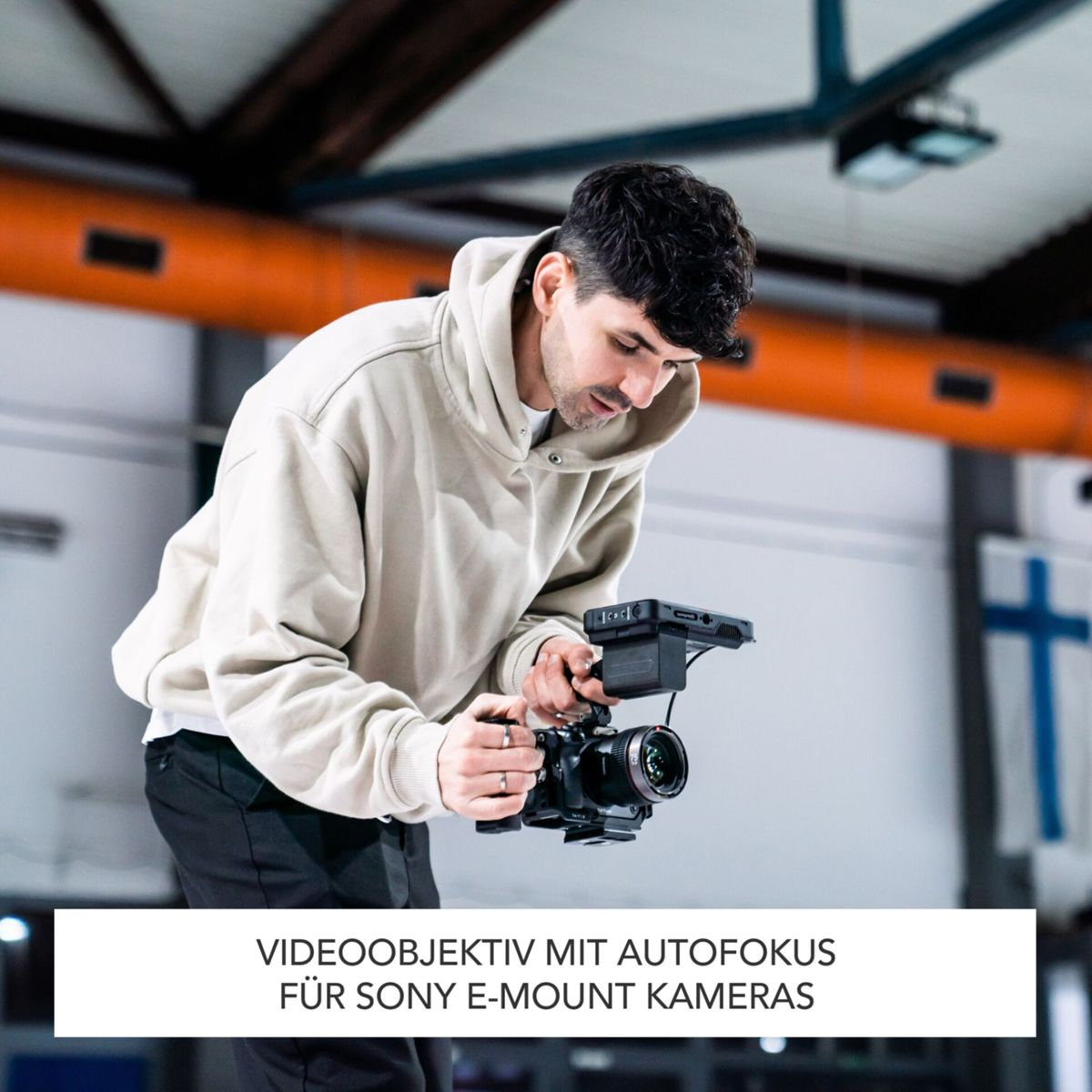 Ein Mann filmt mit einer Kamera. Text: 'VIDEOOBJEKTIV MIT AUTOFOKUS FÜR SONY E-MOUNT KAMERAS'.