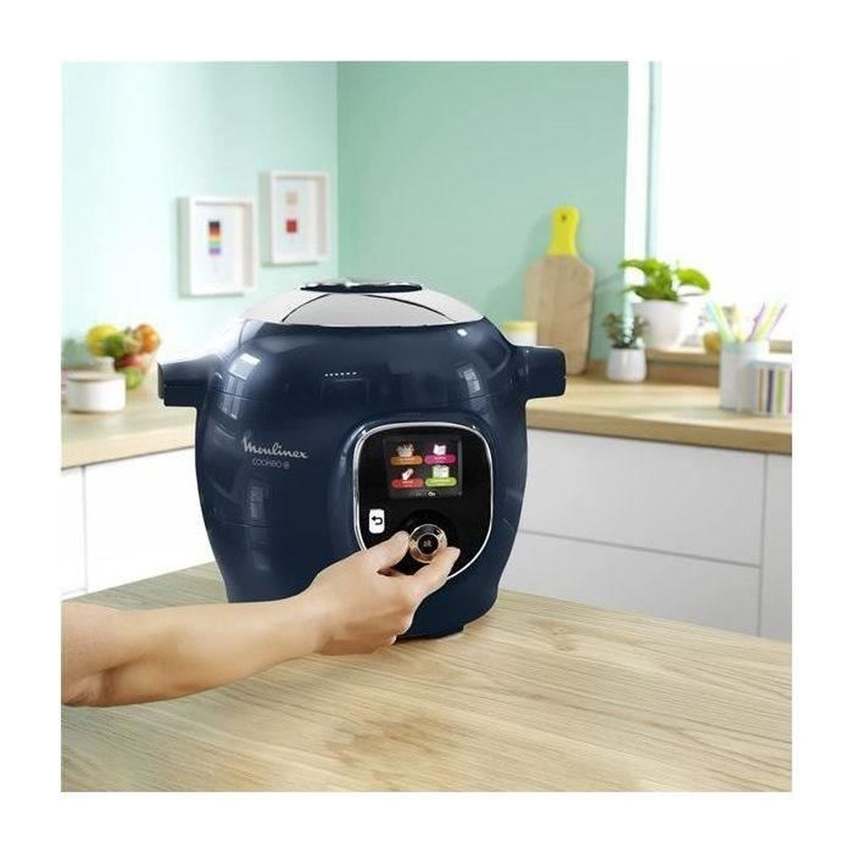 Multicuiseur intelligent Moulinex Cookeo bleu foncé sur un plan de travail en bois. Une main ajuste le cadran.