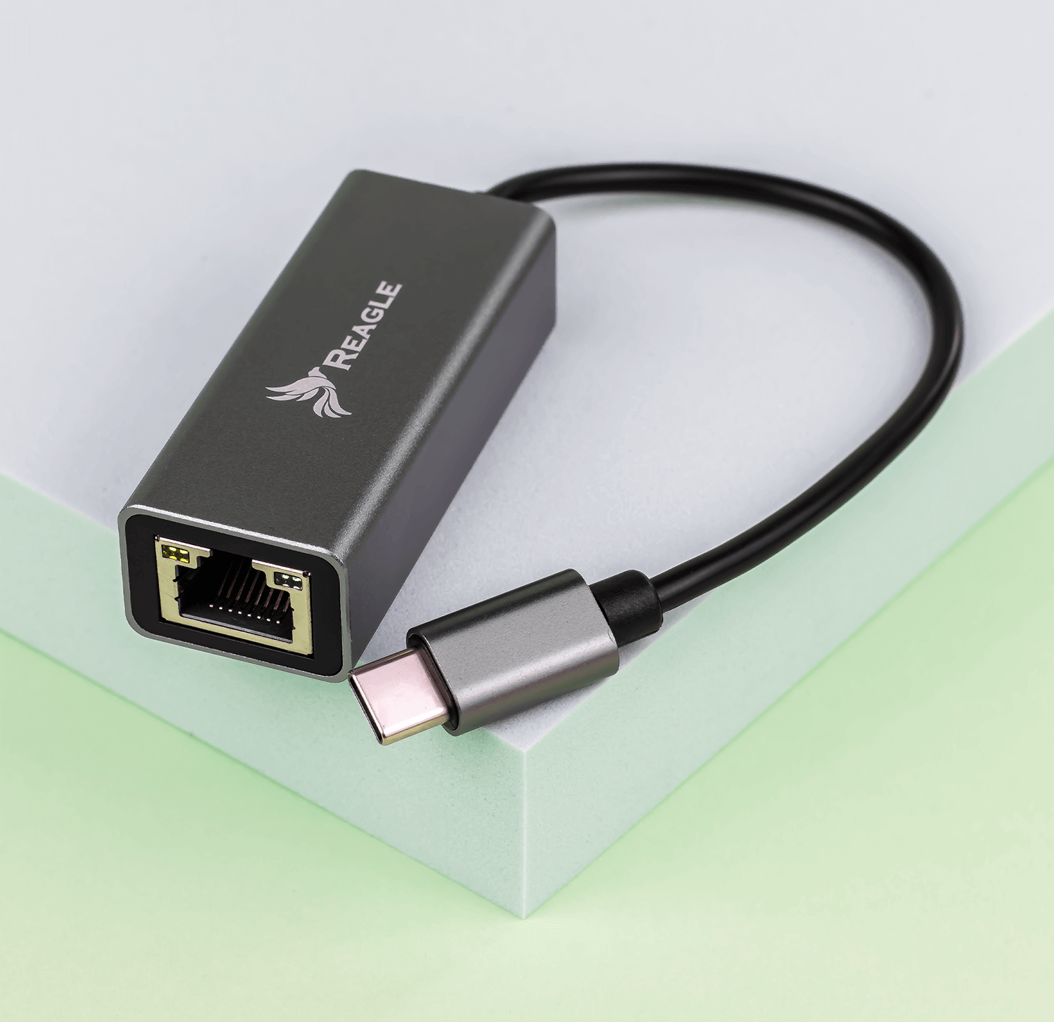 Szary adapter sieciowy z czarnym kablem i złączem USB-C, na podstawce.