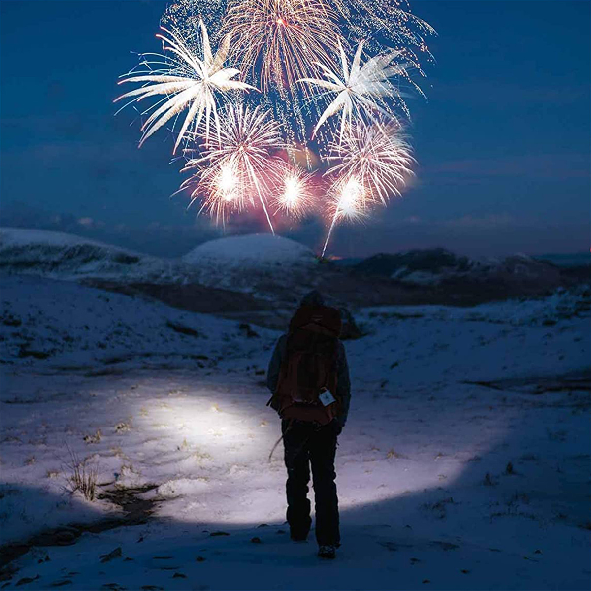 Person geht auf schneebedecktem Boden. Feuerwerk am Himmel.