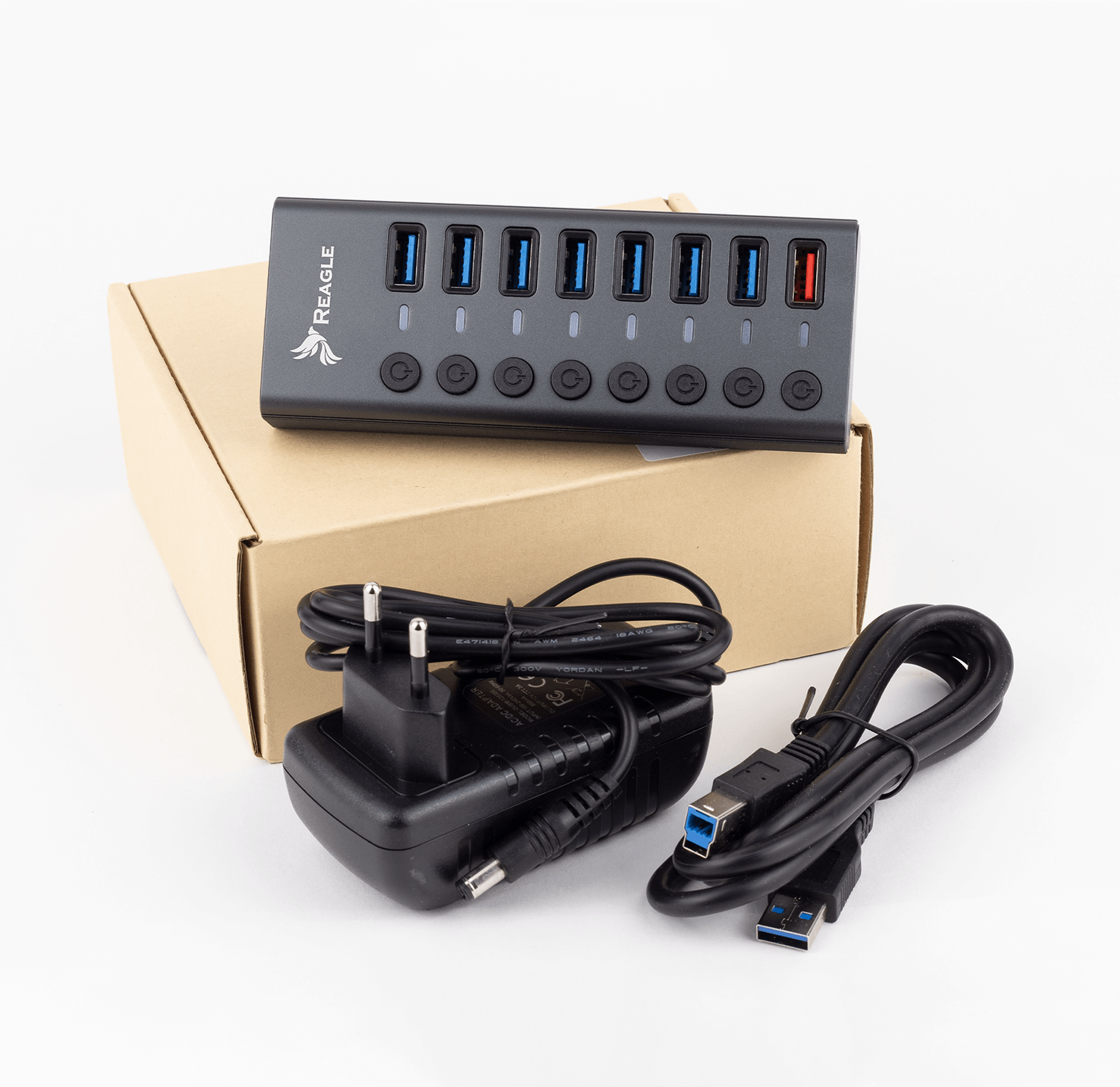 Hub USB z zasilaczem i kablem na białej powierzchni. Hub ma 7 portów.