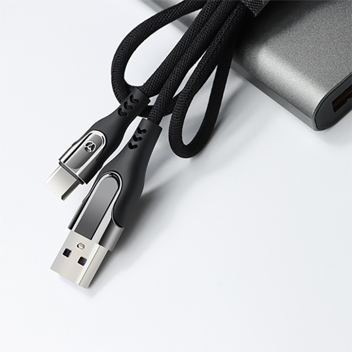 Schwarze USB-C- und USB-Kabel, graue Powerbank. Weiße Oberfläche.