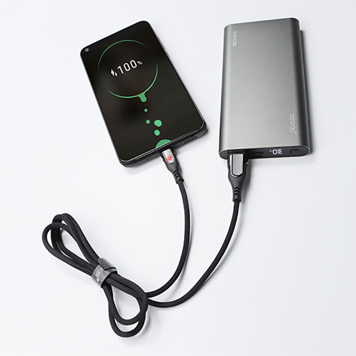 Telefon, der über ein schwarzes Kabel von einer Powerbank geladen wird.