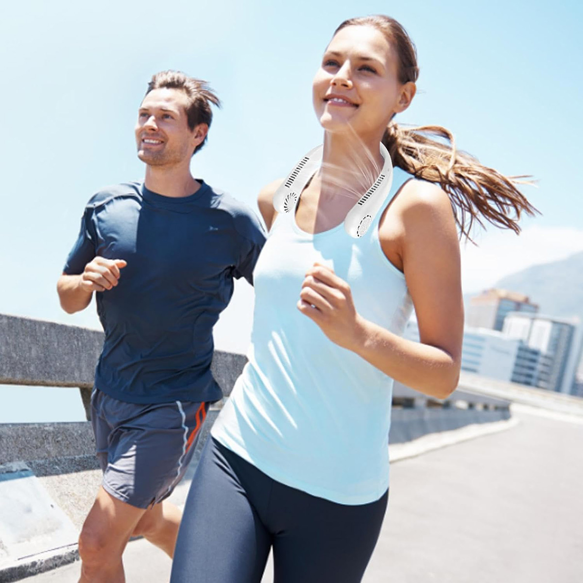 Dos personas corriendo al aire libre. Mujer usa ventilador de cuello. Día soleado.