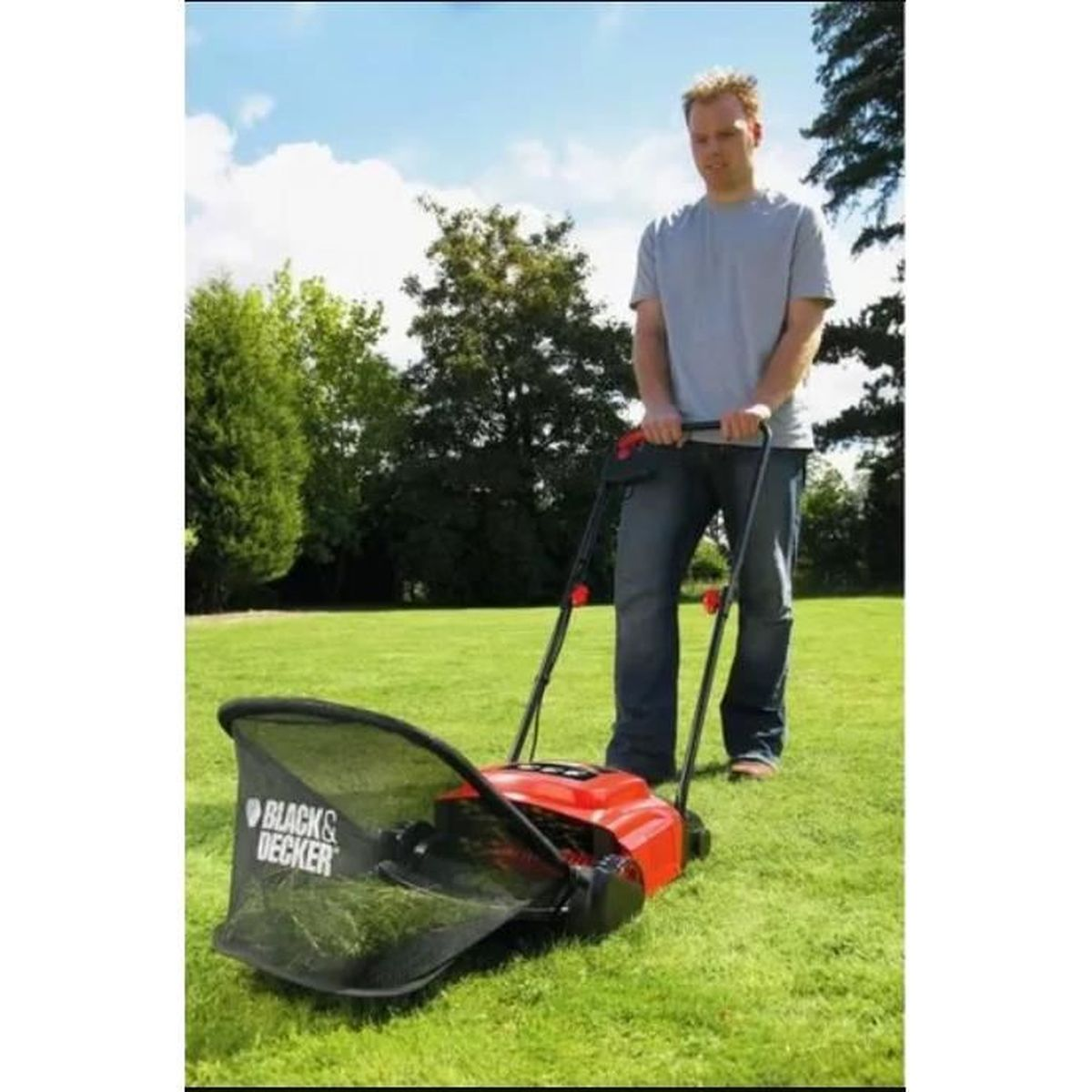 Mann mäht Rasen mit einem rot-schwarzen Rasenmäher auf grünem Feld unter blauem Himmel.