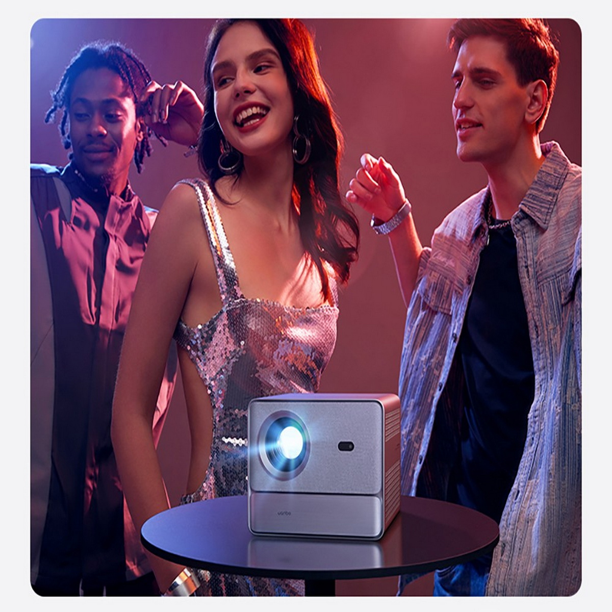 Gente disfrutando de una fiesta con un proyector que muestra una luz brillante sobre una mesa.