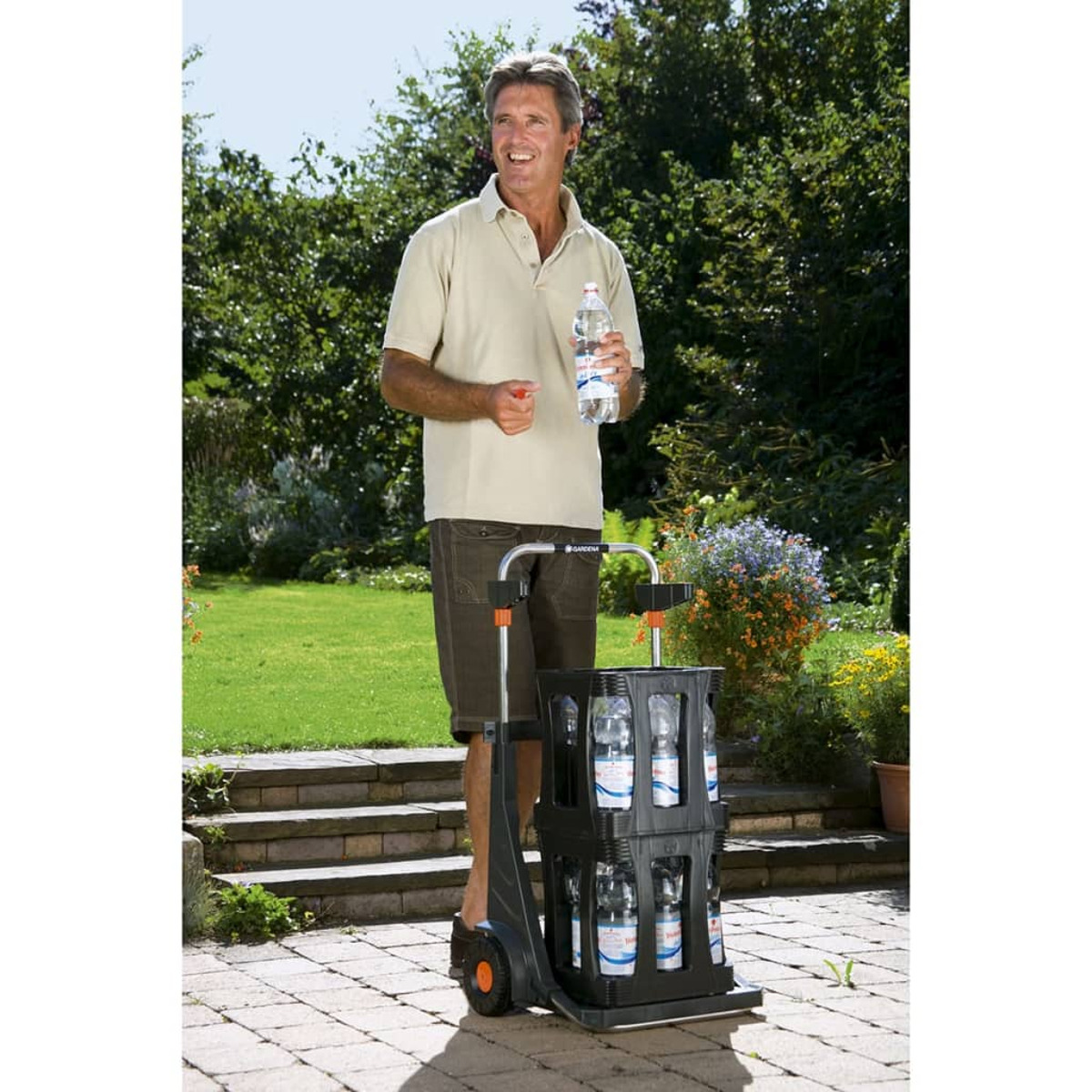 Mann mit beigem Poloshirt hält eine Wasserflasche neben einem Wagen mit Wasserflaschen.