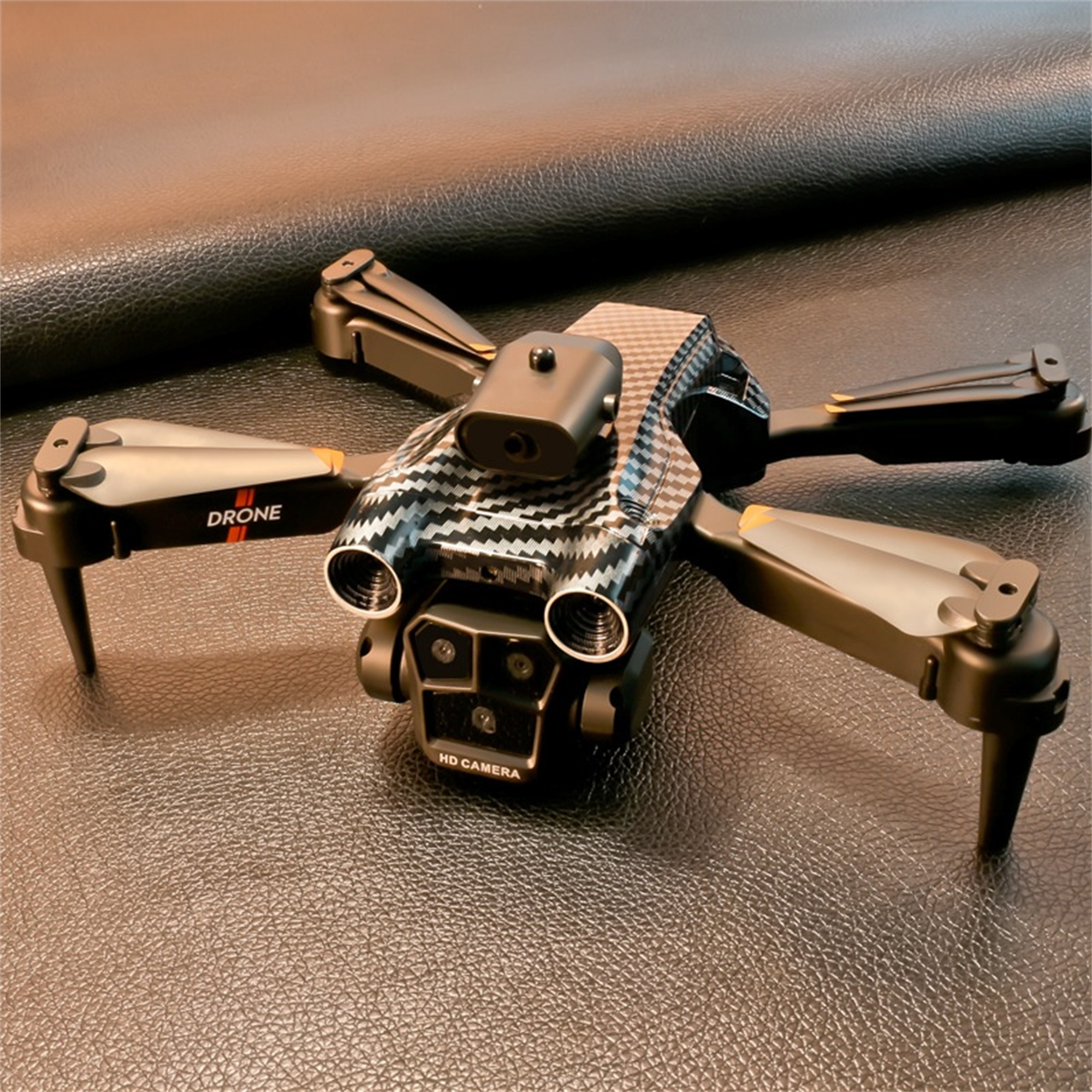 Eine Drohne mit schwarzen und grauen Propellern auf einer Lederoberfläche. Es steht Drone und HD Camera.