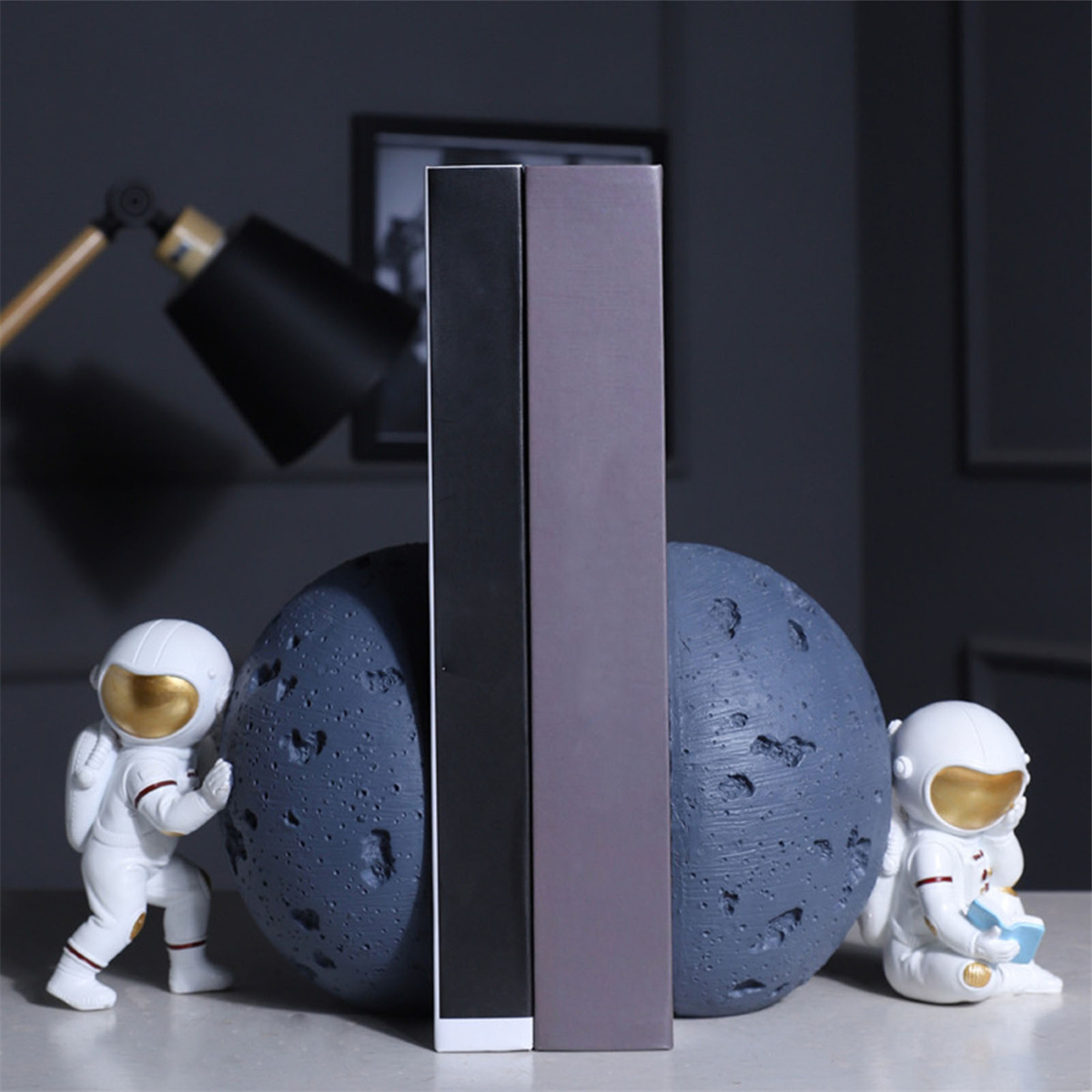 Buchstützen mit Astronauten- und Monddesign. Zwischen ihnen befinden sich Bücher.