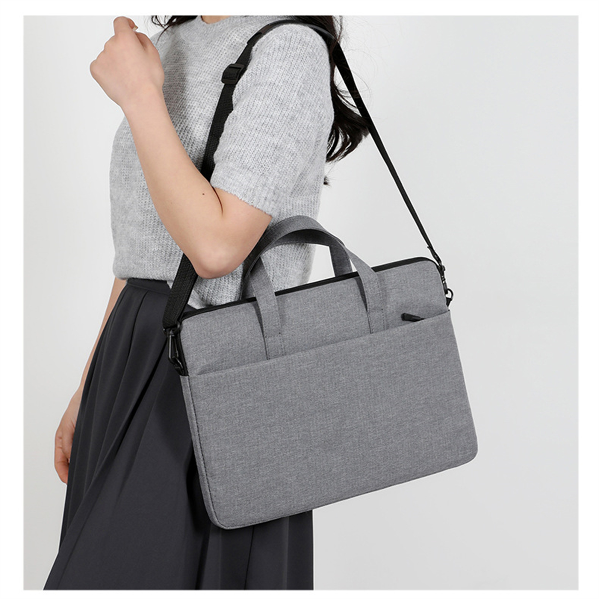 Frau in grauer Kleidung trägt eine graue Laptoptasche mit Schulterriemen.