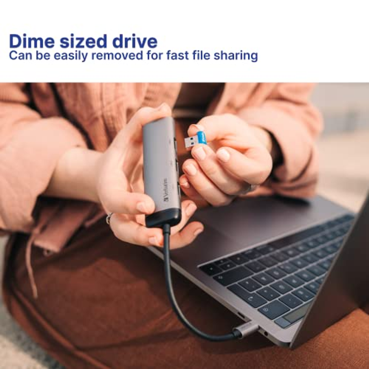 Osoba korzystająca z laptopa z szarym hubem i napędem USB.