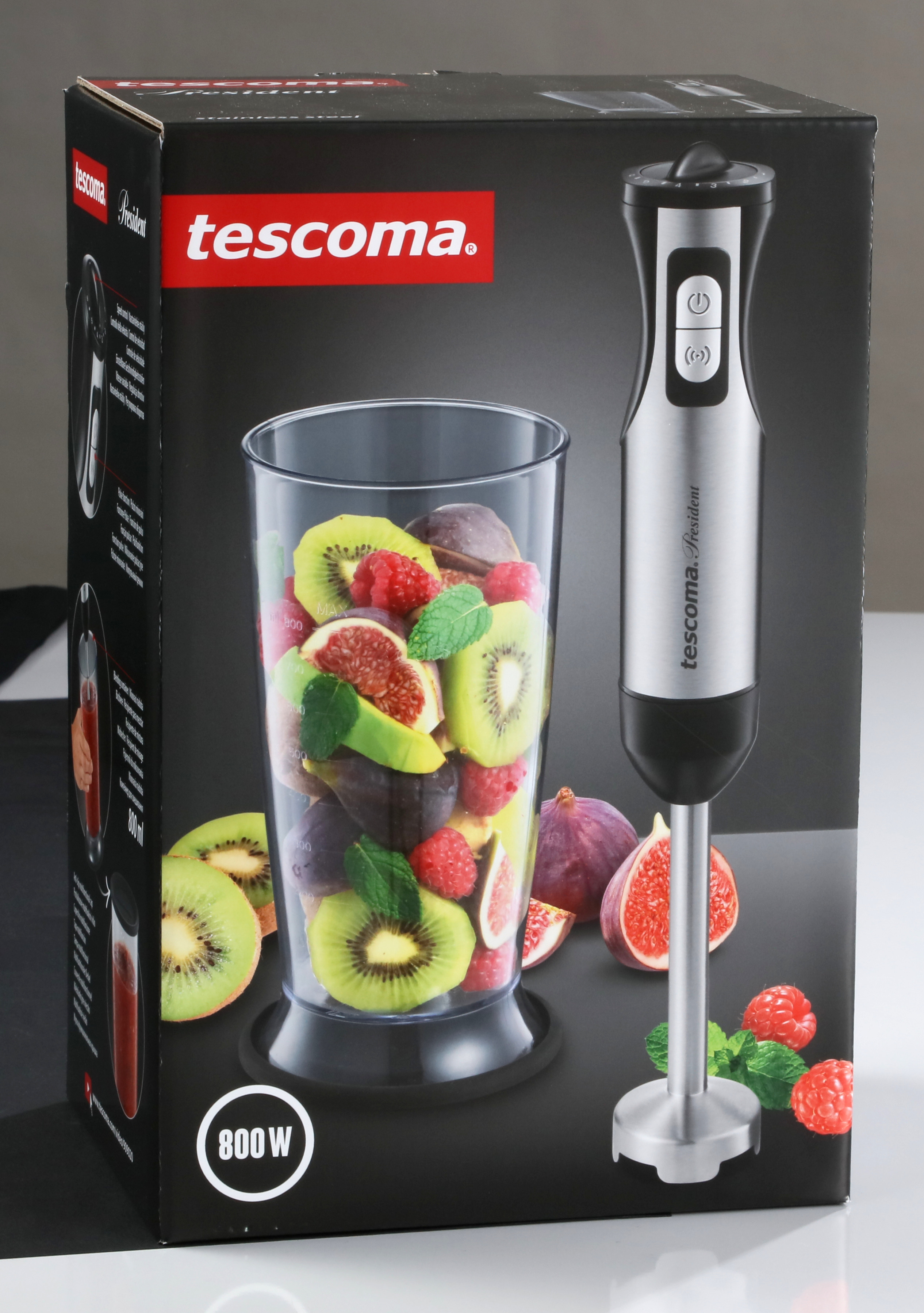 Ein Mixer mit einem Glas voller Früchte und Beeren neben der Box. Schwarzer Hintergrund.