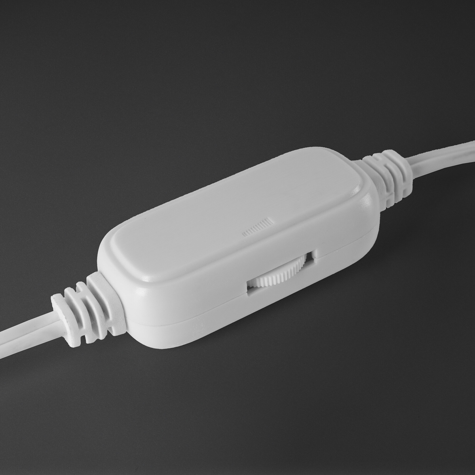 Cavo bianco con un interruttore dimmer, posizionato su uno sfondo grigio scuro. Primo piano.