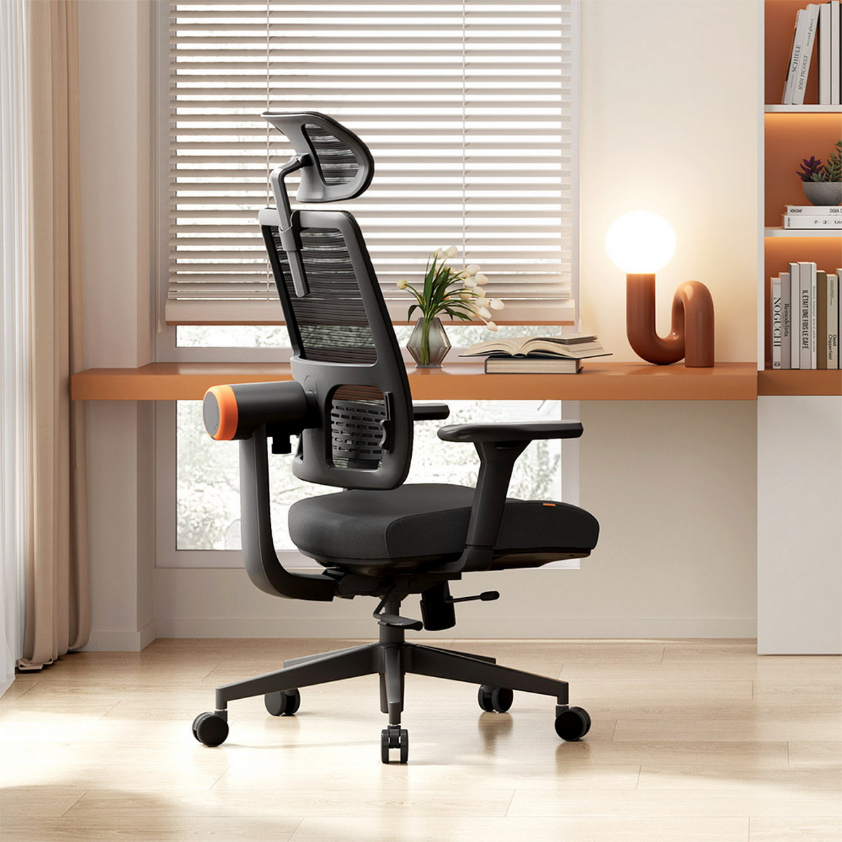 Sedia da ufficio ergonomica nera e arancione. Ha un poggiatesta ed è vicino a una finestra e una scrivania.